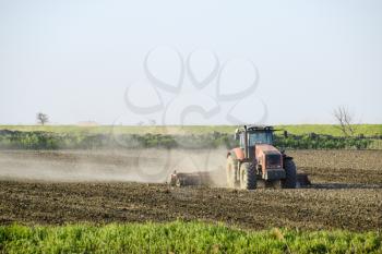 A tractor with a plow lays the soil. Soil cultivation on the field for sowing.