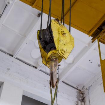 Hoist with winch and hook. A tool for moving goods in a production room. Mechanization of labor.