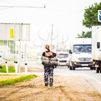 Krasnodar, Russia - June 1, 2017: Hitchhiking. Girl auto-stopper. The girl with the backpack stops the car. Voting on the track.