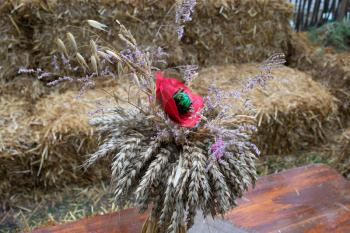 Still life on the tables of summer cafe. A bouquet of wheat spikes and a poppy flower.