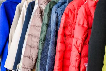 Coats and jackets on hangers in the store. Sale of outerwear