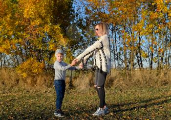 Mother and son are playing in the autumn forest.