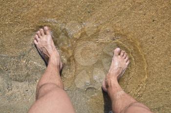 Legs men on the sea sand near sea wave. Walk on the beach.