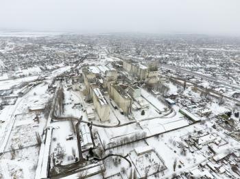 Sprinkled with snow grain elevator. Winter view of the old Soviet elevator. Winter view from the bird's eye view of the village. The streets are covered with snow.