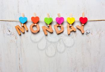 word Monday from wooden letters with colored clothespins on a white wooden background