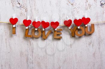 wood letters and heart forming phrase I LOVE YOU on old wooden white  background