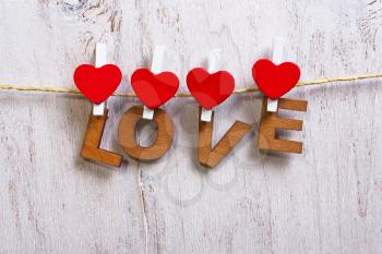 Red heart with love word decoration hanging over white wood background, Valentine day concept.