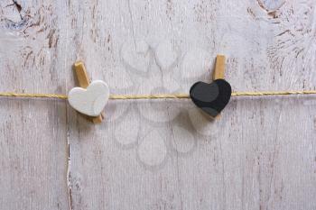 Two lovely white and Black  hearts -  hanging on the clothesline. On old white wood background.