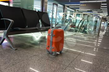 Orange suitcase in the waiting room, at the airport, at the station. Concept travel