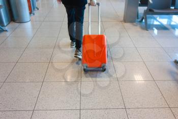 man, a girl is driving an orange suitcase in the waiting room, at the airport. Concept travel