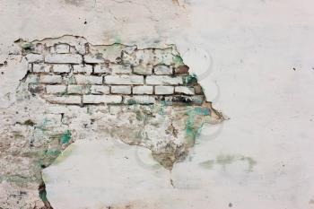 Wall of plaster with white and green paint, and brick. 