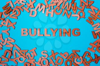 Word Bullying of wooden letters on a blue background. The problem of violence, trolling