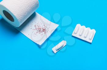  suppository and toilet paper on a blue background, for the treatment of hemorrhoids
