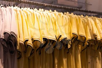 Men's clothing, fashionable, stylish on hangers in stores. The concept of shopping, sales. Yellow T-shirts
