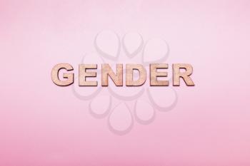 The word gender in wooden letters on a pink background