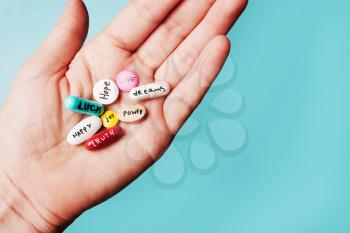 The concept of creative pills, a placebo in the hand, with joy, love, happiness, truth, power, dream on a blue background
