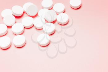 White, round pills on a pink background. The concept of the treatment of the disease, healthcare, women's health.