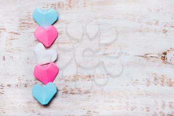 Origami paper hearts in transgender flag colors on wooden background