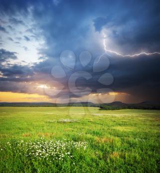 Meadow in mountain. Rain cloud and lightning. Nature composition.