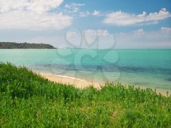 Spring coast on the sea. Sky, sea, and green grass. Nature composition.