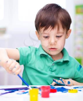 Portrait of a cute little boy playing with paints