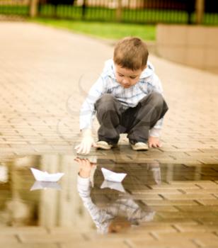 Cute little boy is playing with paper boat