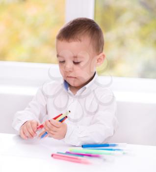 Cute little boy is writing using a pen in preschool