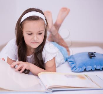 Cute little girl is reading a book