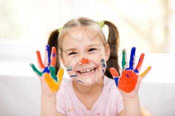 Portrait of a cute cheerful girl showing her hands painted in bright colors