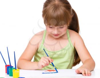 Cute thoughtful child play with paints while sitting at table, isolated over white