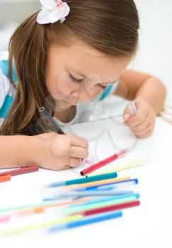 Cute little girl is writing using a pen in preschool