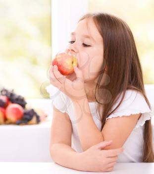 Portrait of a cute cheerful little girl with red apple