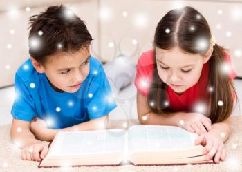 Happy children is reading book, over snowy background