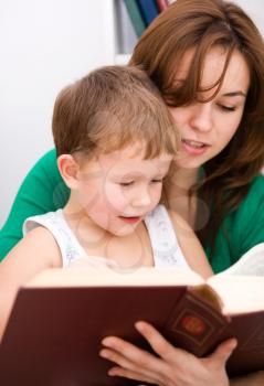 Mother is reading book with her son, indoor shoot