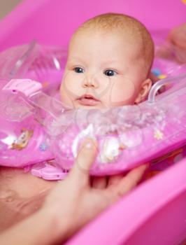 Cute baby girl enjoying bath, laughing while splashing water