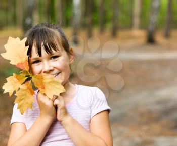 Happy girl in autumn park hiding behind a tree