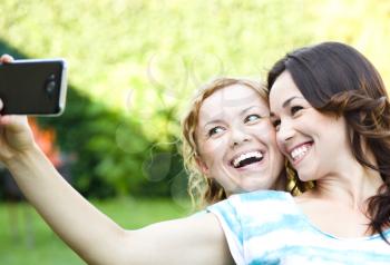 Happy girls having fun taking selfie outdoors. together. sisters, friends