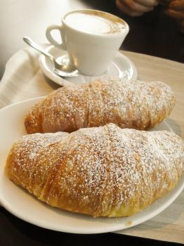 Sweet pastries, flaky croissants with black cofee on a white plate
