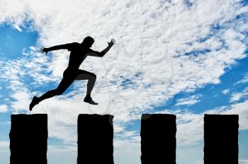 Business risk concept. Running businessman jumps over cliffs