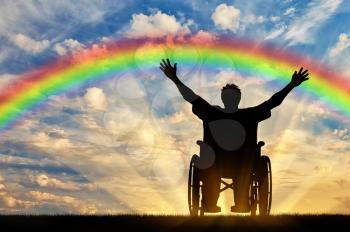 Disabled concept. Happy disabled person in a wheelchair is happy rainbow at sunset