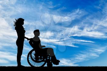 Concept of disability and disease. Silhouette of disabled person with a guardian against the sky