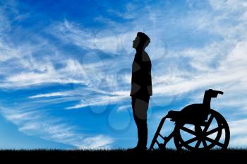 Concept of disability and disease. Silhouette of disabled and wheelchair daytime