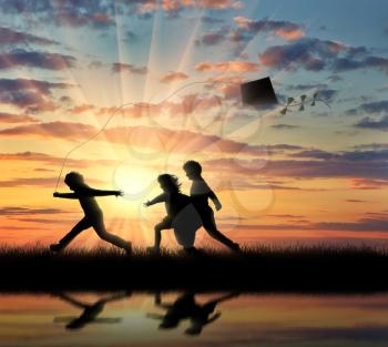 Silhouette of children playing with a kite sunset near the river and their reflection in wate. Friendship concept.