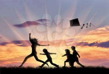 Woman and three children play with kite on the nature. Concept of family and happiness