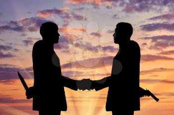  Concept of business betrayal. Silhouette of two businessmen shaking hands and keep arms behind his back weapon