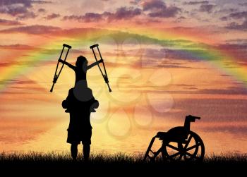 Happy disabled child on father's shoulders holding crutches and wheelchair and rainbow on sea. Concept happy child disabled