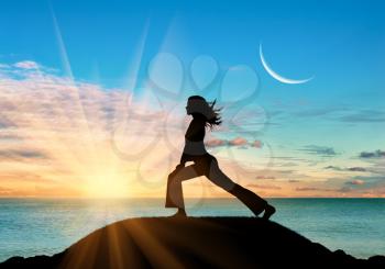Concept of meditation and relaxation. Silhouette of a girl practicing yoga class on a background of sea sunset