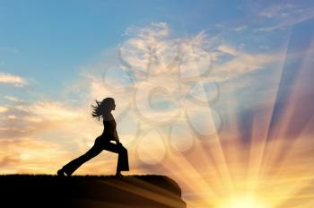 Concept of meditation and relaxation. Silhouette of a girl practicing yoga exercise on the sunset background