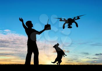 Silhouette of a flying drone, and a man with a remote control and dog at sunset. Concept quadrocopters