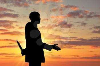 Concept of business betrayal. Silhouette of a businessman shaking hands and holding a knife behind his back